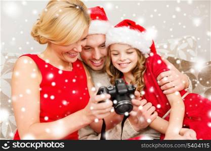 family, christmas, x-mas, winter, happiness and people concept - smiling family in santa helper hats looking at pictures