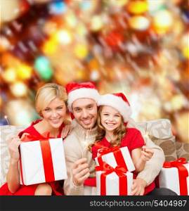 family, christmas, x-mas, winter, happiness and people concept - smiling family in santa helper hats with many gift boxes and bengal lights