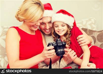 family, christmas, x-mas, winter, happiness and people concept - smiling family in santa helper hats looking at pictures