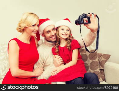 family, christmas, x-mas, winter, happiness and people concept - smiling family in santa helper hats taking picture with photo camera