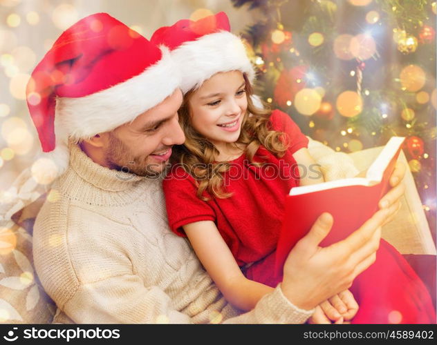 family, christmas, x-mas, winter, happiness and people concept - smiling father and daughter in santa helper hats reading book