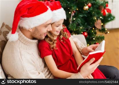 family, christmas, x-mas, winter, happiness and people concept - smiling father and daughter in santa helper hats reading book