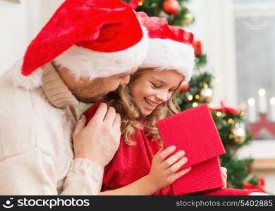 family, christmas, x-mas, winter, happiness and people concept - smiling father and daughter in santa helper hats opening gift box