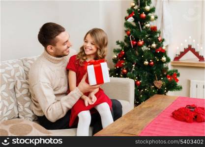 family, christmas, x-mas, winter, happiness and people concept - smiling father and daughter holding gift box and looking at each other