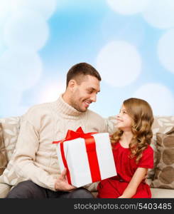 family, christmas, x-mas, winter, happiness and people concept - smiling father and daughter holding gift box and looking at each other