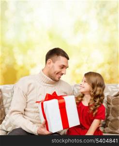 family, christmas, x-mas, winter, happiness and people concept - smiling father and daughter holding gift box and looking at each other