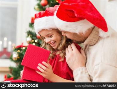 family, christmas, x-mas, winter, happiness and people concept - smiling father and daughter in santa helper hats opening gift box