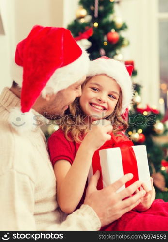 family, christmas, x-mas, winter, happiness and people concept - smiling father and daughter in santa helper hats opening gift box