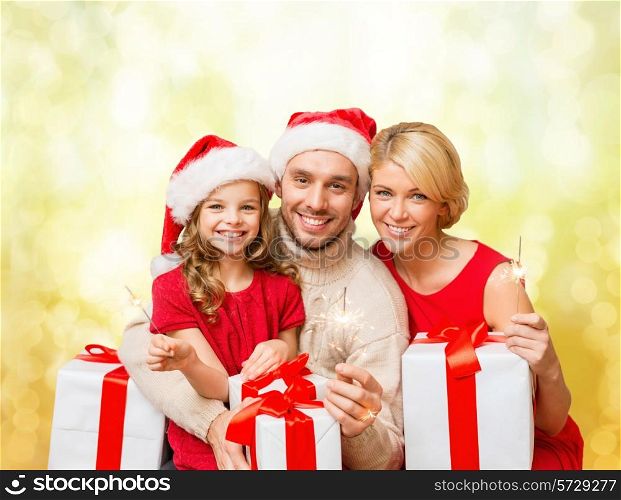 family, christmas, xmas, happiness and people concept - smiling family in santa helper hats with many gift boxes and bengal lights