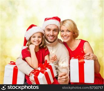 family, christmas, xmas, happiness and people concept - smiling family in santa helper hats with many gift boxes and bengal lights
