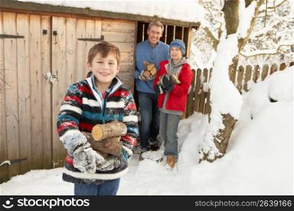 Family Collecting Logs From Wooden Store In Snow