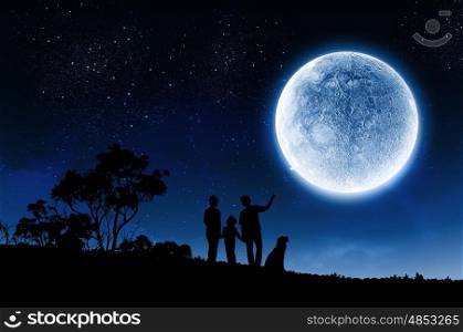 Family concept. Silhouettes of happy family at night under full moon