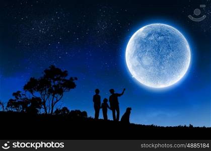 Family concept. Silhouettes of happy family at night under full moon