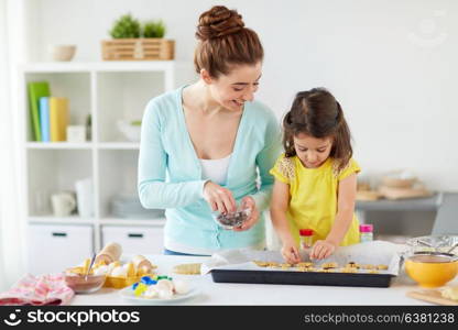 family, cooking and baking concept - happy mother and little daughter with chocolate sprinkles decorating cookies on tray at home kitchen. happy mother and daughter making cookies at home