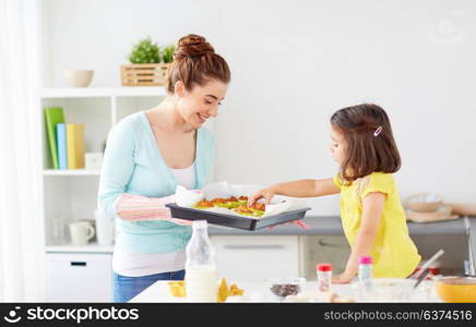family, cooking and people concept - mother and little daughter baking muffins at home kitchen. mother and daughter baking muffins at home