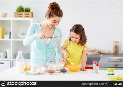 family, cooking, baking and people concept - happy mother and little daughter with sieve sifting flour and making dough at home kitchen. happy mother and daughter baking at home