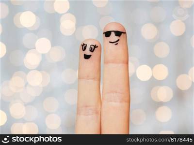 family, couple, people and body parts concept - close up of two fingers with smiley faces over holidays lights background