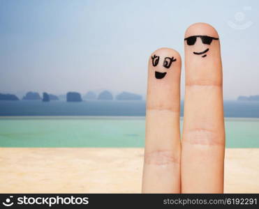 family, couple, travel, tourism and body parts concept - close up of two fingers with smiley faces over beach or infinity edge pool background
