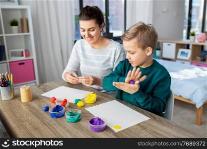 family, creativity and craft concept - mother and little son playing with modeling clay at home. mother and son playing with modeling clay at home