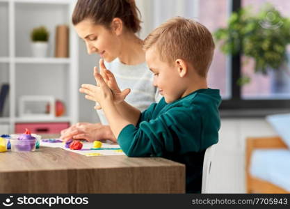 family, creativity and craft concept - mother and little son playing with modeling clay at home. mother and son playing with modeling clay at home