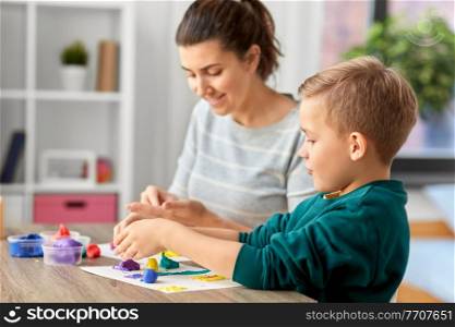 family, creativity and craft concept - mother and little son playing with modeling clay at home. mother and son playing with modeling clay at home