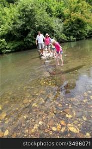 Family crossing river in summer