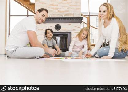 Family drawing together in a living room. Family with two children drawing together in a living room sitting on the floor