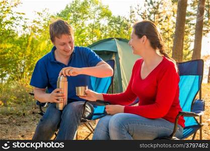 family drinking tea next to the tent near Pine