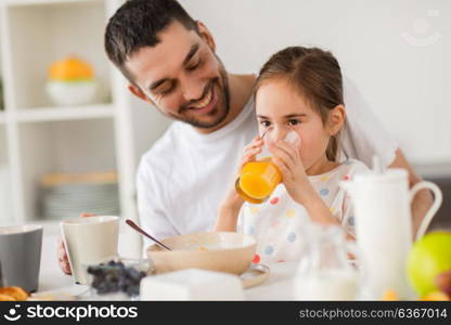 family, eating and people concept - happy father and daughter having breakfast at home. happy family having breakfast at home