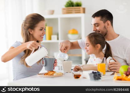 family, eating and people concept - happy mother, father and daughter having breakfast at home. happy family having breakfast at home