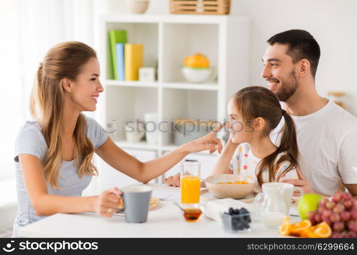 family, eating and people concept - happy mother, father and daughter having breakfast at home. happy family having breakfast at home