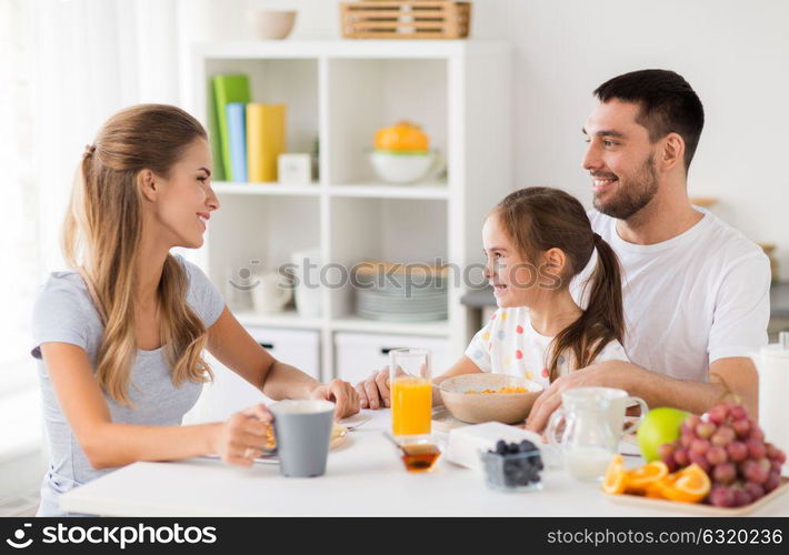 family, eating and people concept - happy mother, father and daughter having breakfast at home. happy family having breakfast at home