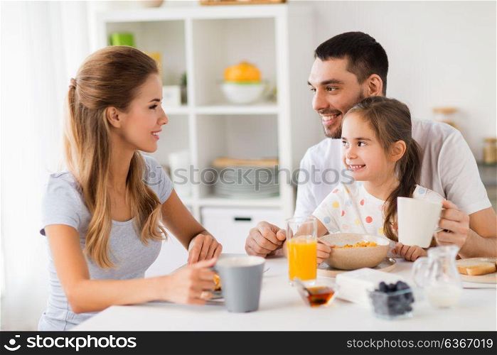 family, eating and people concept - happy mother, father and daughter having breakfast at home. happy family having breakfast at home