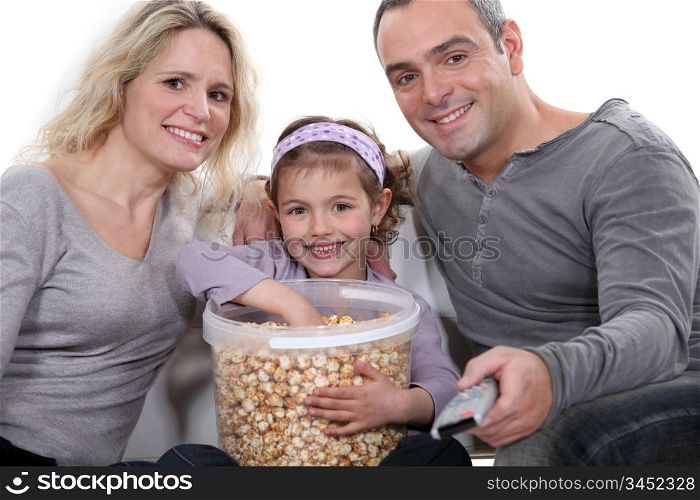 Family eating popcorn in front of television