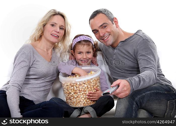 Family eating popcorn on a sofa