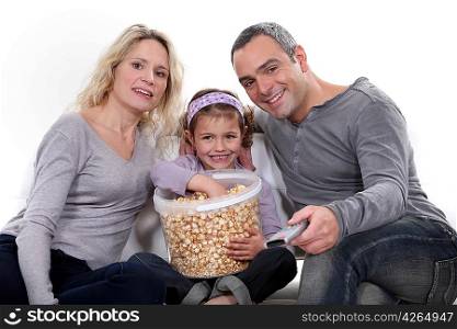 Family eating popcorn on a sofa
