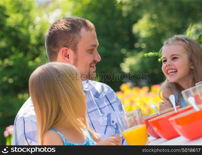 Family eating together outdoors at park on backyard