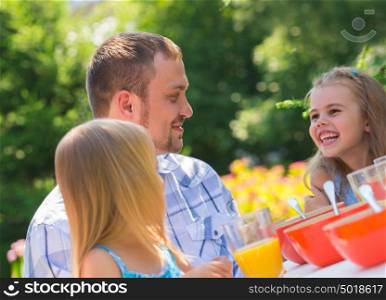 Family eating together outdoors at park on backyard