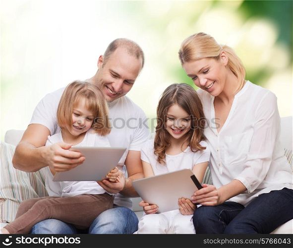 family, ecology, technology and people - smiling mother, father and little girls with tablet pc computers over green background