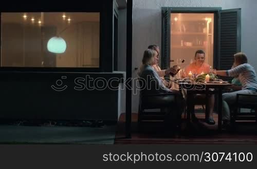 Family enjoying meal on terrace together in the evening time