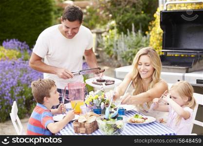 Family Enjoying Outdoor Barbeque In Garden