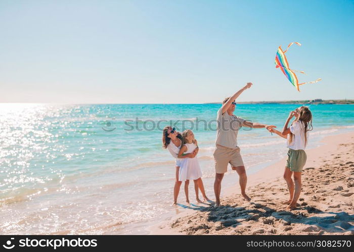 Family enjoying vacation on the beach flying a kite. Happy young family with two kids with flying a kite on the beach