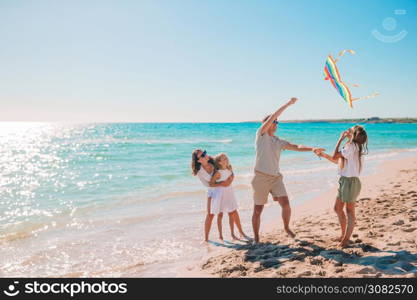 Family enjoying vacation on the beach flying a kite. Happy young family with two kids with flying a kite on the beach