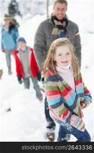 Family Enjoying Walk Through Snowy Landscape