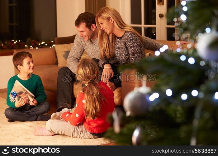 Family Exchanging Gifts By Christmas Tree