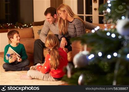 Family Exchanging Gifts By Christmas Tree