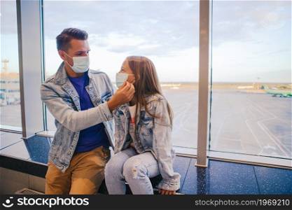 Family Father and child wear facemask during coronavirus and flu outbreak. Travel during a pandemic. Dad and little girl with medical masks at airport. Protection against Coronavirus and gripp