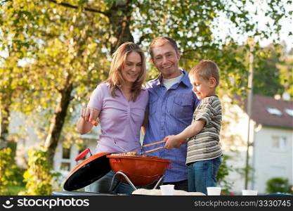 Family - father and son - having a barbecue party, the child is very concentrated on doing the cooking work