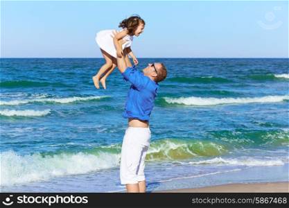Family father holding daughter playing on the beach shore