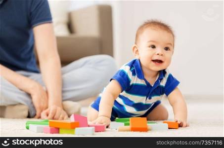 family, fatherhood and childhood concept - baby boy and father playing with toy blocks at home. baby boy with father playing toy blocks at home